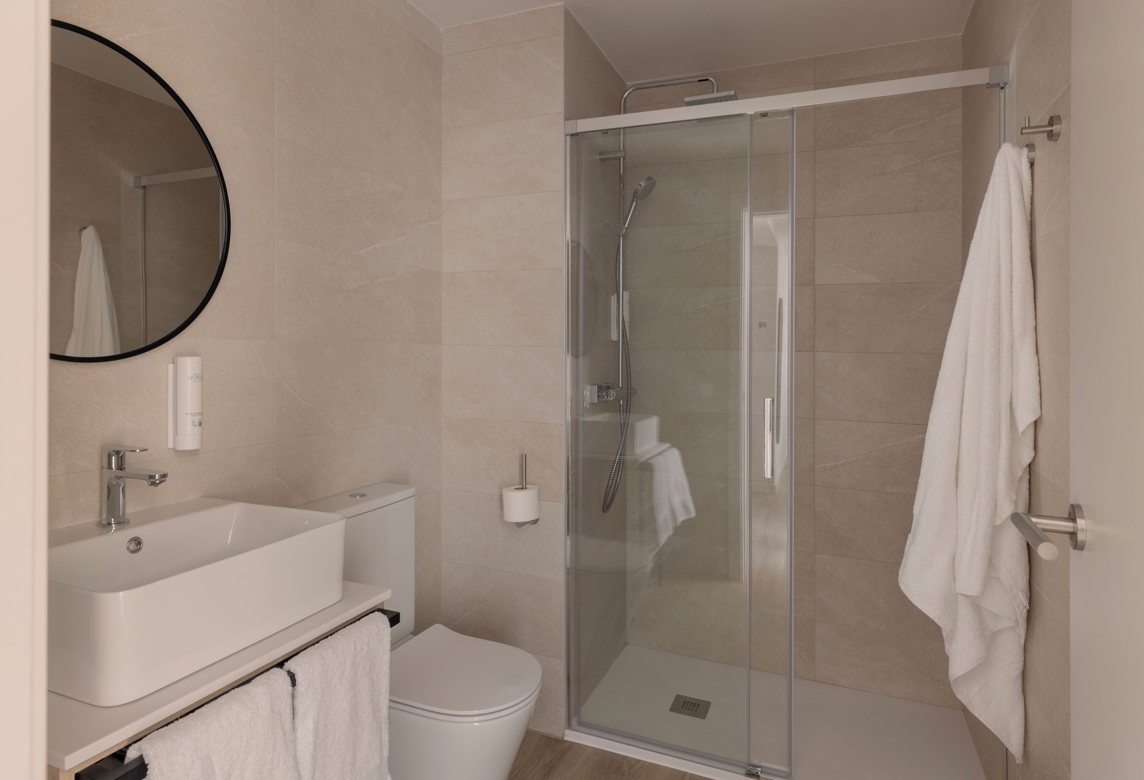 Un baño moderno con ducha envuelta en vidrio, lavamanos e inodoro.