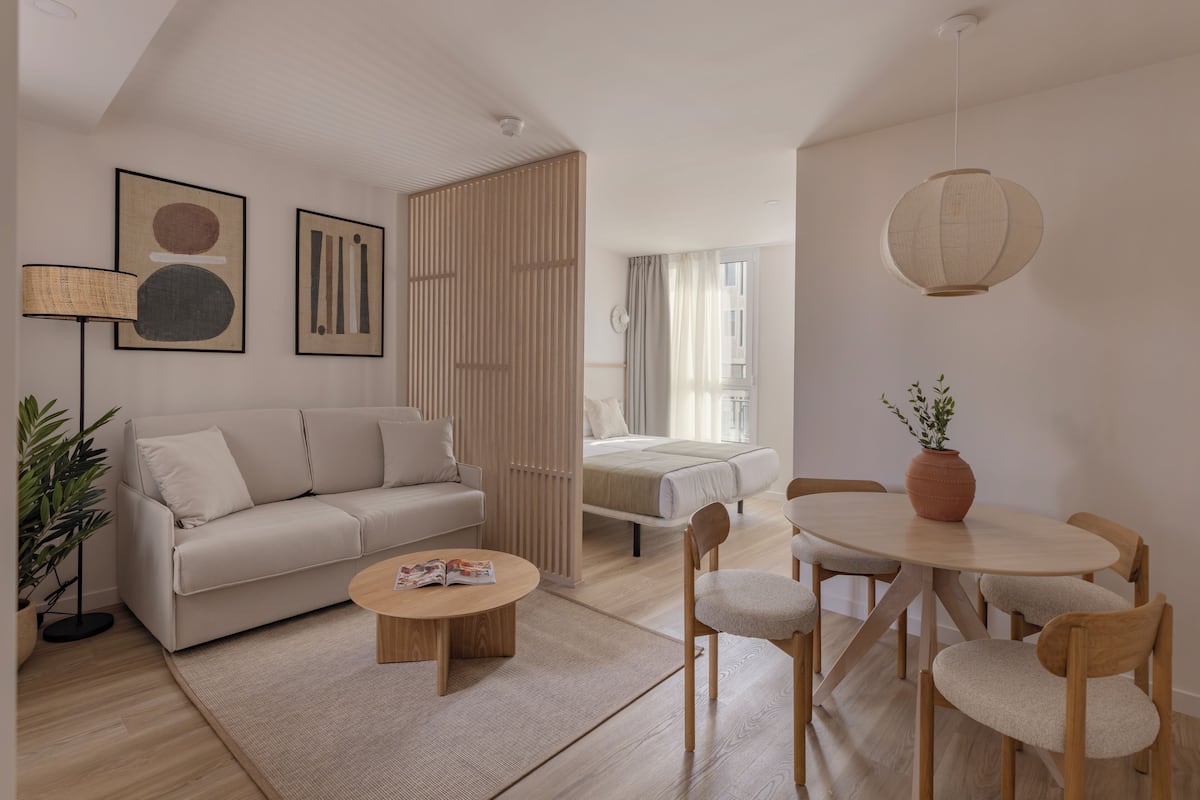 A modern living room with a sofa, coffee table, and dining area with chairs.