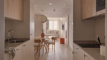 Een moderne keuken met houten kastjes, een eethoek met een ronde tafel en stoelen, en een lichtgekleurde vloer.