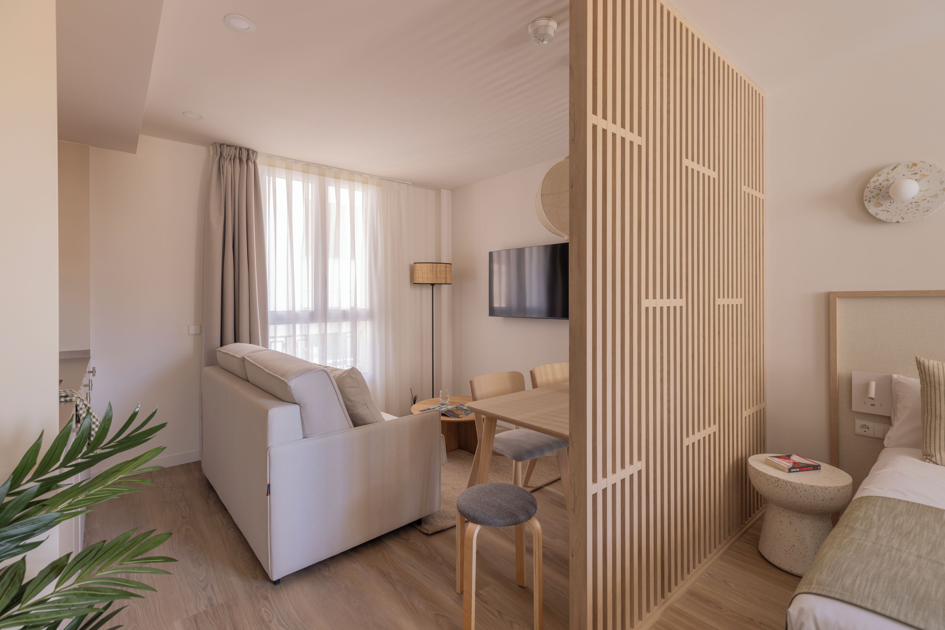 Een moderne hotelkamer met een bank, een eettafel en een televisie.