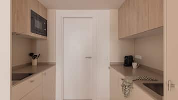 Una cocina compacta con armarios de madera, microondas, cafetera y lavabo.