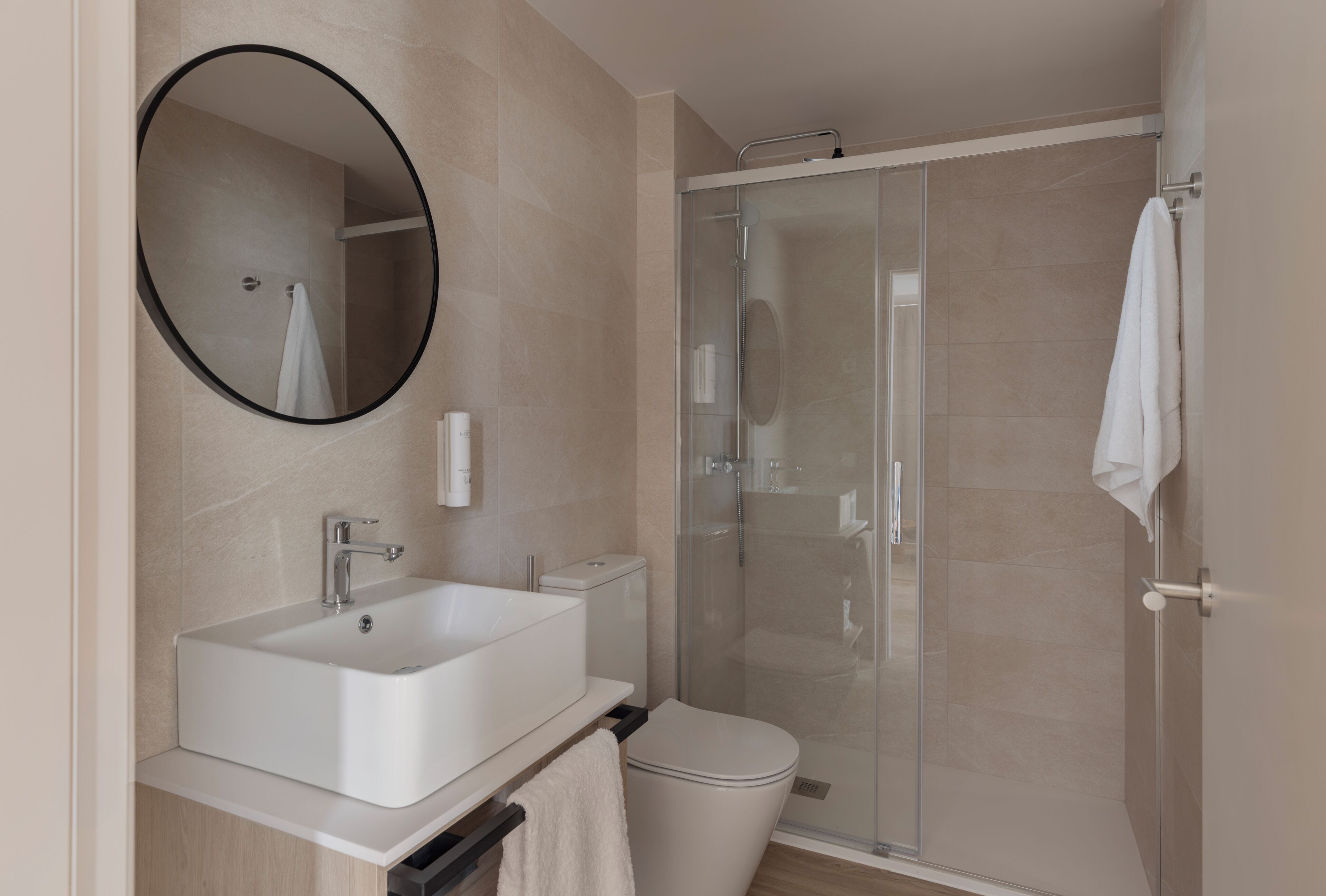 A modern bathroom with a sink, toilet, and glass-enclosed shower.