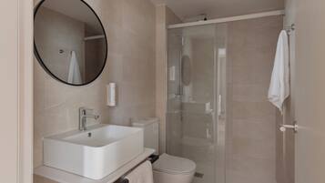 A modern bathroom with a sink, toilet, and glass-enclosed shower.