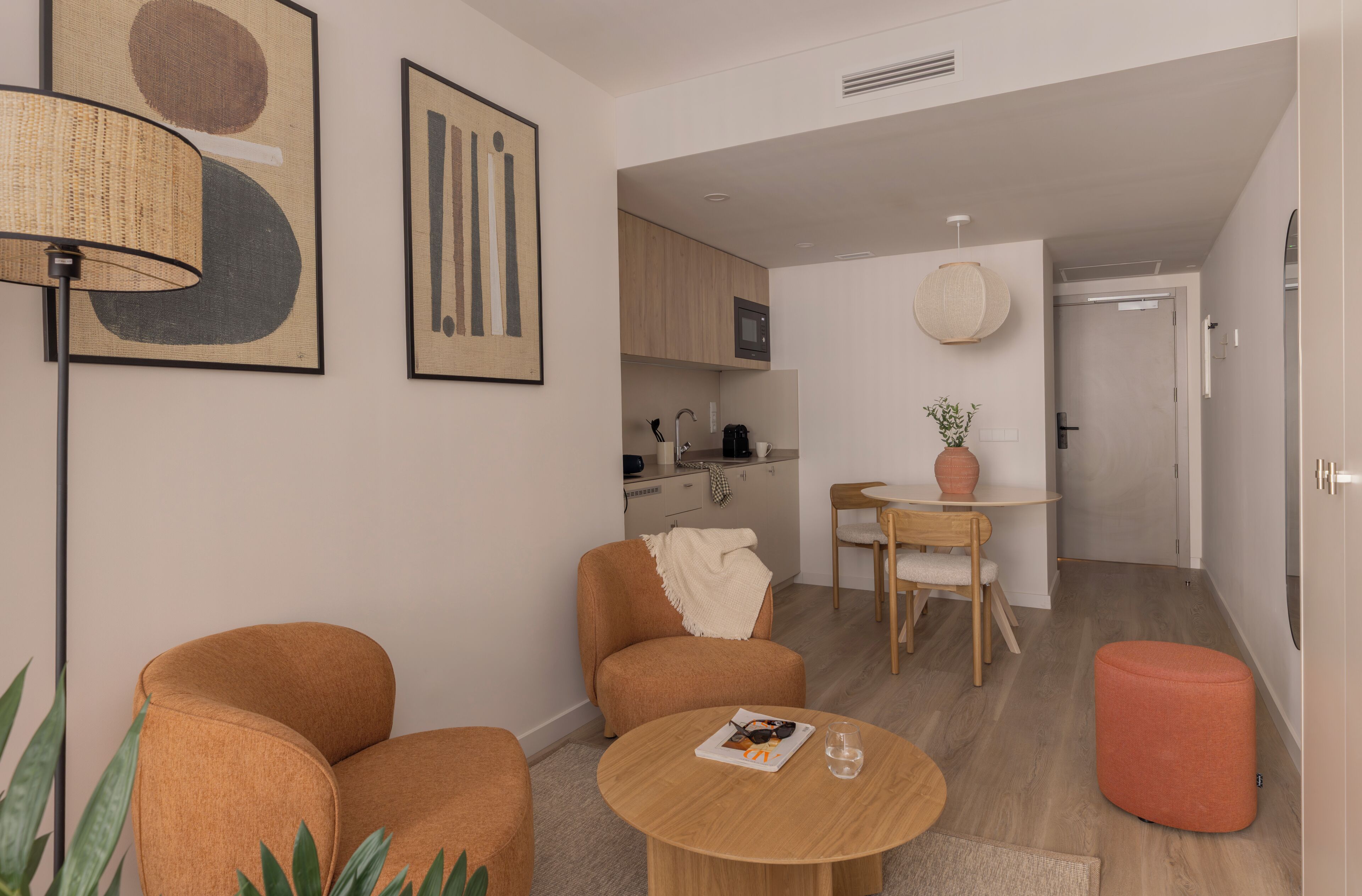 A modern living room with a sofa, a round table, and a small orange ottoman.