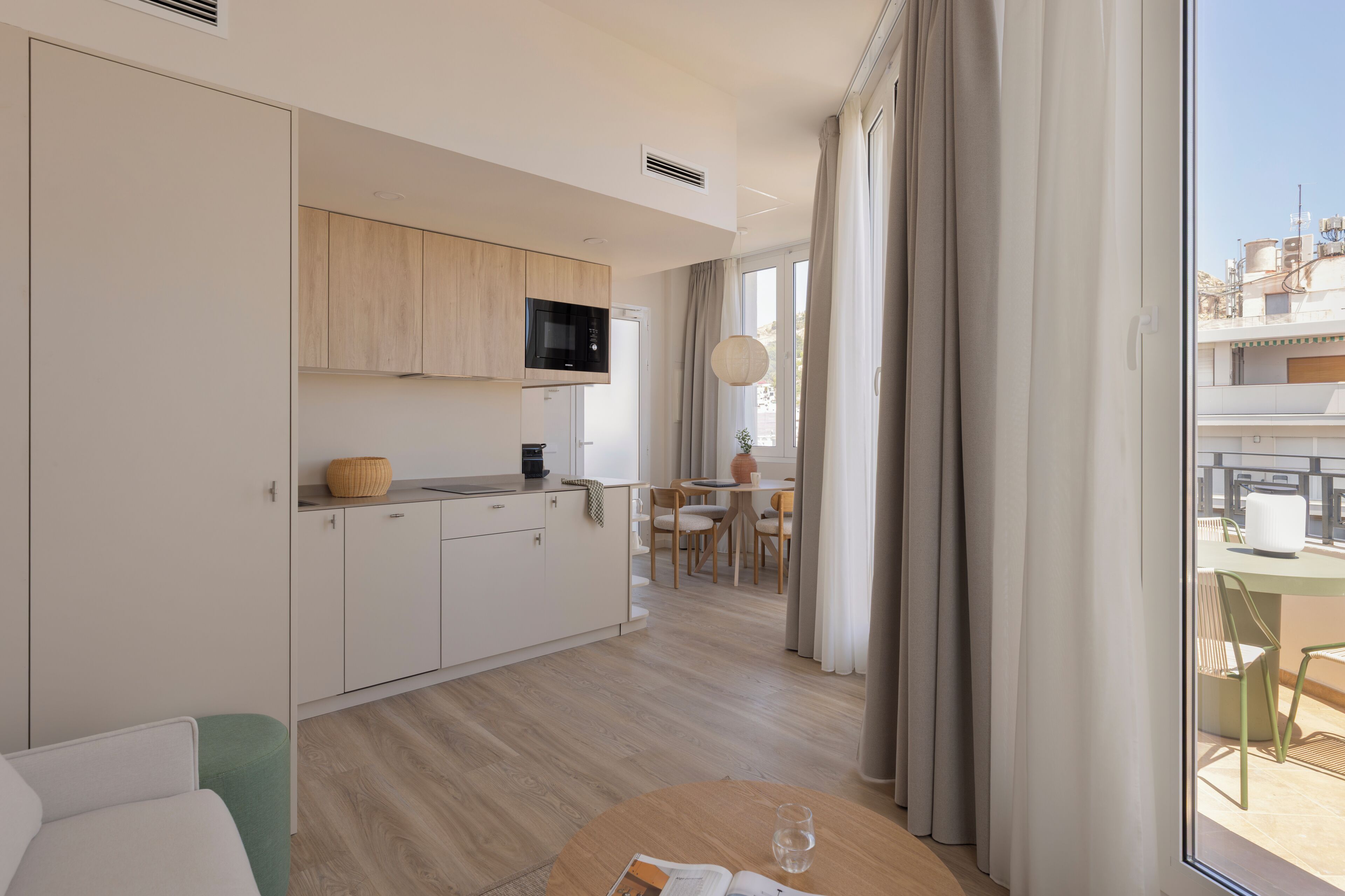 Una cocina moderna con microondas, cafetera y zona de comedor con mesa y sillas.