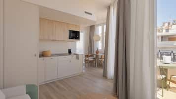 Una cocina moderna con microondas, cafetera y zona de comedor con mesa y sillas.