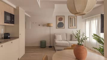 A modern kitchen with a microwave, a dining table with chairs, a green ottoman, and a large woven light fixture.