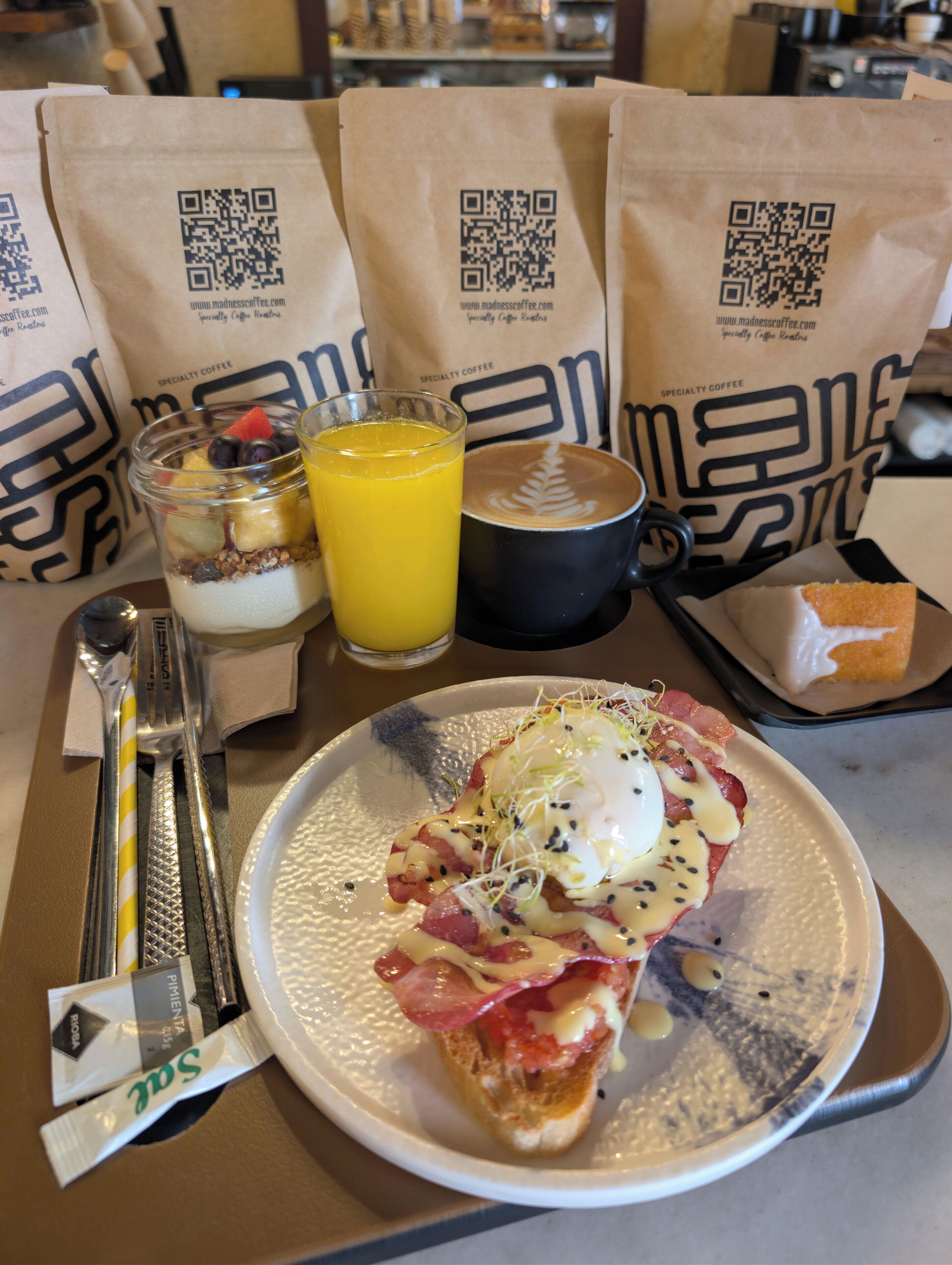 Un plato de desayuno con huevos, tocino y una bebida, acompañado de una cuchara, tenedor y servilleta.