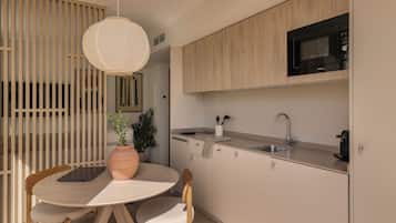 Una cocina moderna con una mesa redonda de comedor, sillas de madera, una lámpara colgante y un microondas integrado.