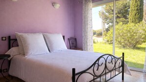 A bedroom with a bed, a nightstand, a lamp, and a view of the outdoors. - Pretty Provencal house in a quiet area 5 minutes walk from the sea in St Croix Martigues (Martigues)
