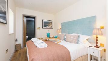 A hotel room with a bed, bedside table, lamp, and a framed picture on the wall.