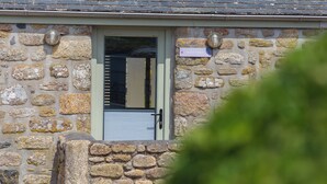 A stone building with a metal door, a small window, and a sign reading 'SCILLY STACK'. - Scilly Stack (Penzance)