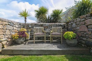 A stone wall, two wooden chairs, a small table, and potted plants. - Scilly Stack (Penzance)