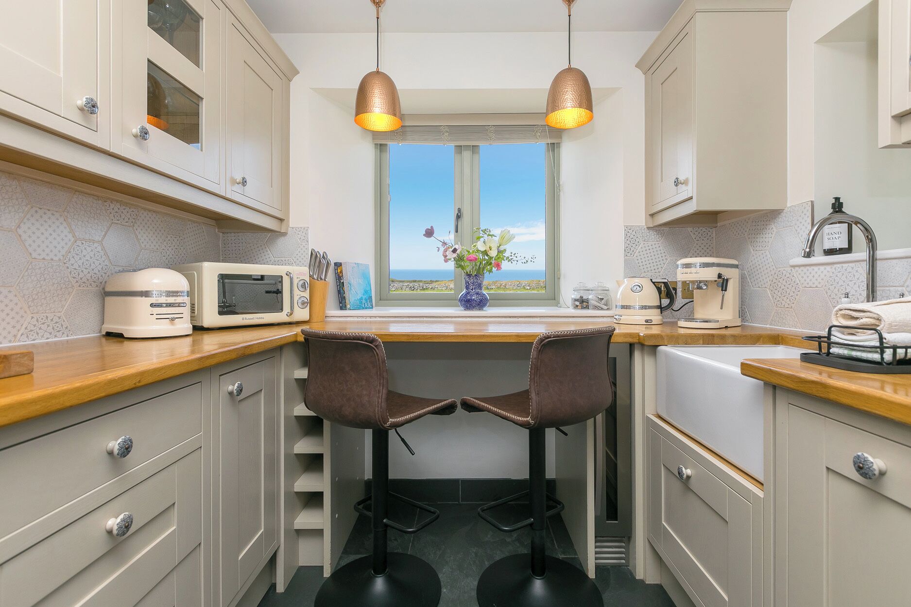 Cocina compacta con vista al exterior, un tostador, una tetera y dos sillas.
