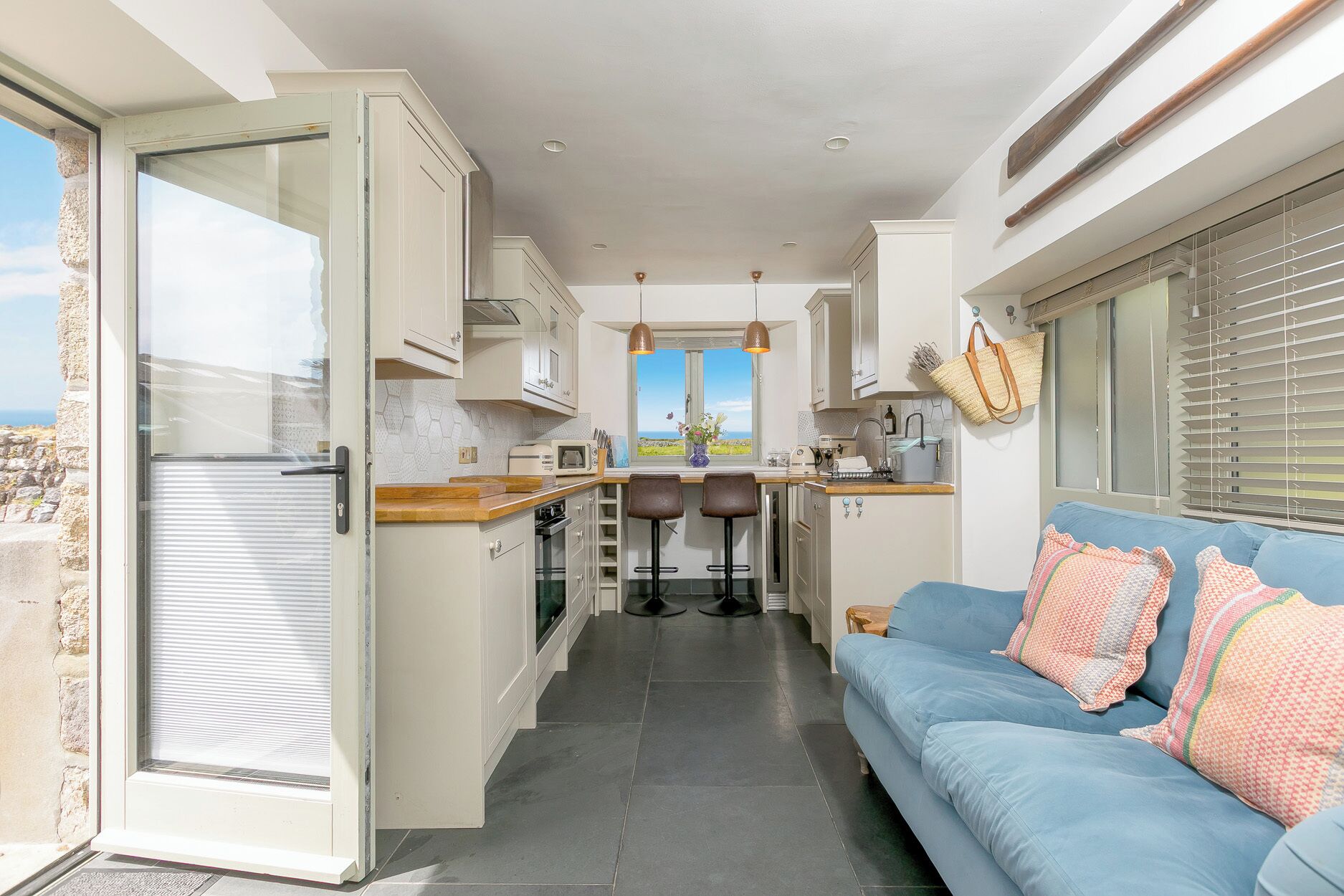 Una cocina compacta con vistas, un sofá azul y una zona de comedor.