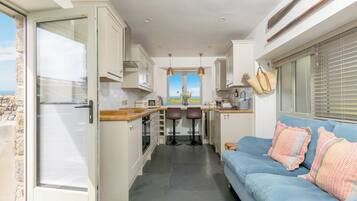 Una cocina compacta con vistas, un sofá azul y una zona de comedor.
