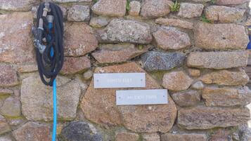 A stone wall with two signs reading 'SANDY FEET' and 'MUDDY PAWS.'