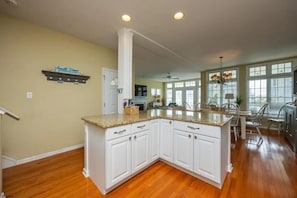 A kitchen with white cabinets, a granite countertop, and a dining area with chairs.