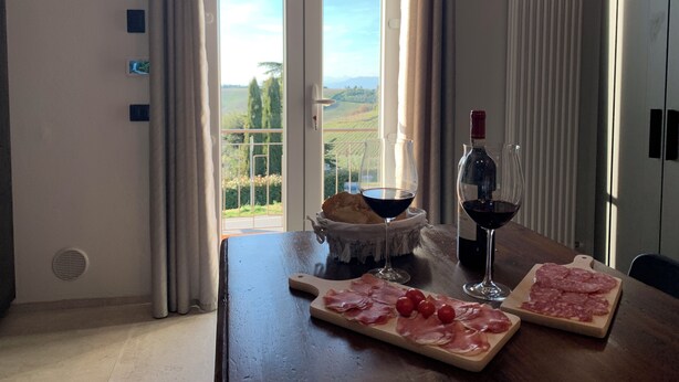 Una mesa de comedor con vistas al campo, una botella de vino y un cuenco de pan.