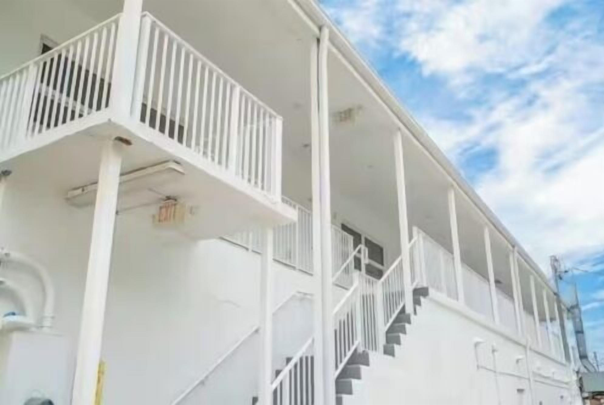 A white building with a balcony and a staircase.