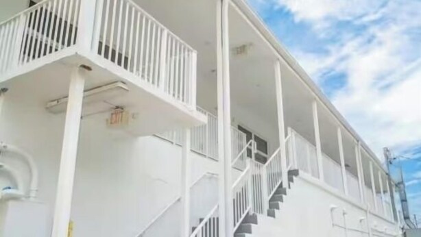 Ein weißes Gebäude mit Balkon und Treppe.