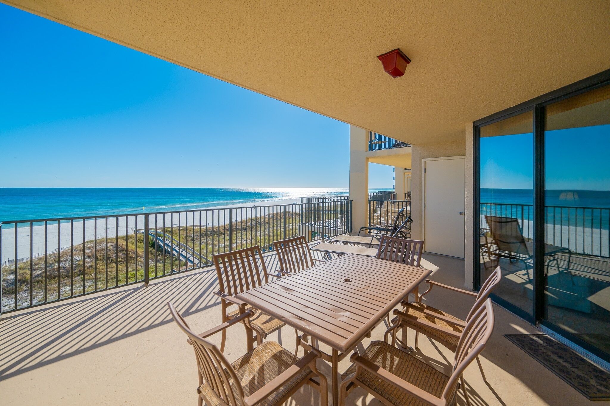 A balcony with a table and chairs overlooking a beach.