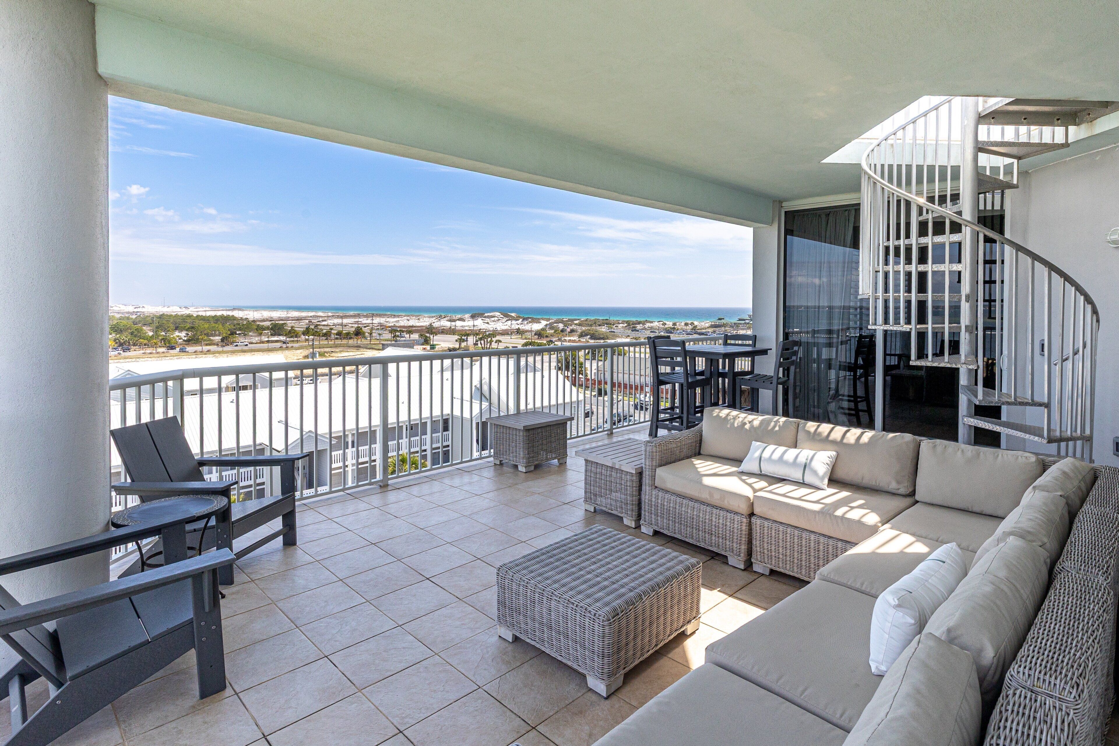 A balcony with outdoor furniture, a spiral staircase, and a view of the beach.