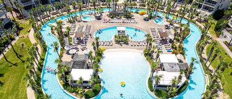 A large, multi-level hotel with a central swimming pool, multiple balconies, and lush landscaping.