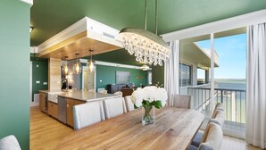 A modern kitchen with a wooden island, a dining area with a wooden table, and a balcony with a view of the ocean. - Destin West Bayside Osprey Ph 01 3 Bedroom Condo (Destin)