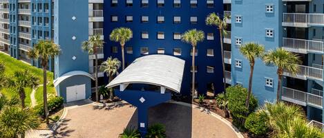 A modern hotel with a blue facade, multiple balconies, and a central curved structure.