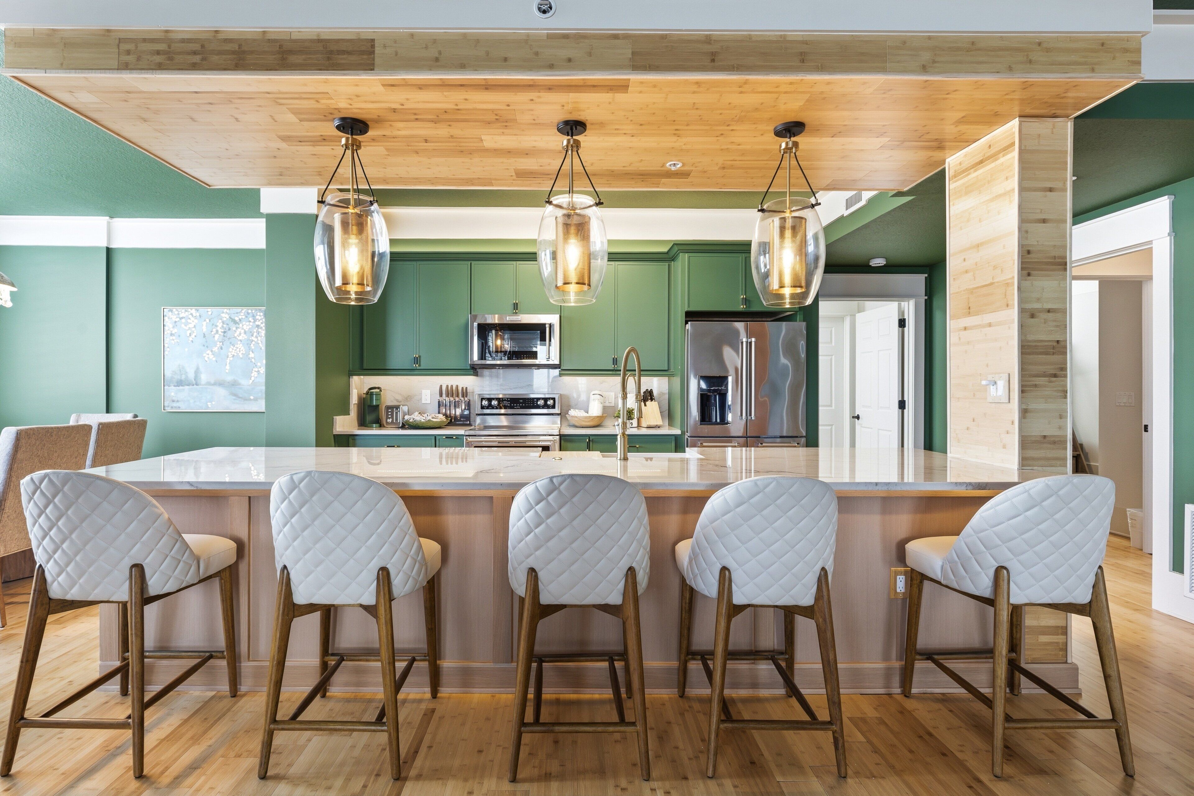 A modern kitchen with a central island, bar stools, and pendant lighting.