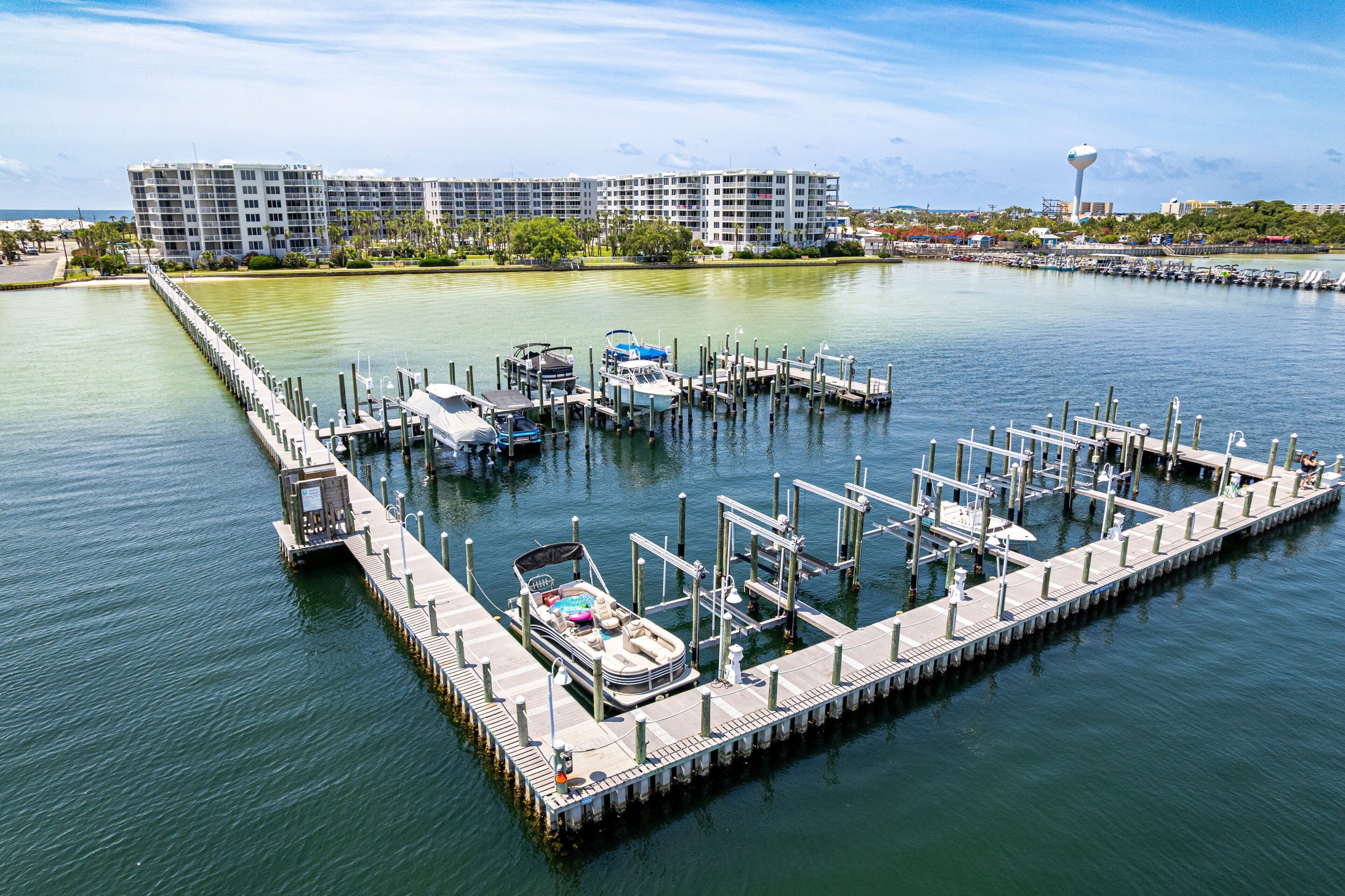 Uma marina com barcos atracados, um cais e um edifício alto ao fundo.