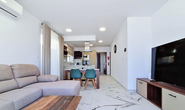 Una sala de estar moderna con un sofá, un televisor y un comedor con sillas y una mesa.