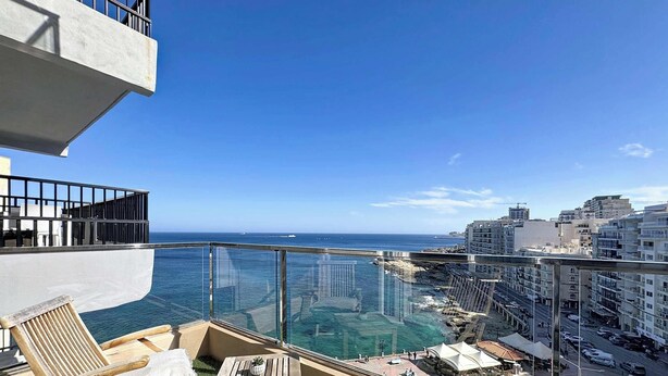 A balcony with a glass railing overlooking a coastal cityscape and the sea. - Bright Sliema Coastal Apartment with Sea Terrace (Tas-Sliema)