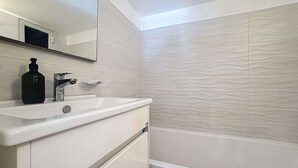 A bathroom with a white sink, a mirror, a black soap dispenser, and a textured wall. - Bright Sliema Coastal Apartment with Sea Terrace (Tas-Sliema)