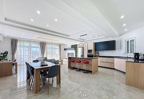 Une cuisine moderne dotée d’un îlot central, de tabourets de bar et d’un coin repas avec une table et des chaises.