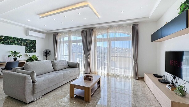 A modern living room with a sofa, coffee table, TV, and large windows. - Scenic Gozo Apartment & Shared Pool (Ix-Xagħra)