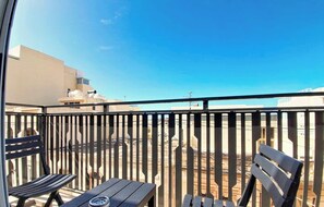 Ein Balkon mit Metallgeländer, einem Holzstuhl und einem Tisch.