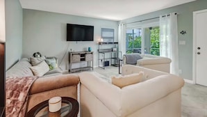 A living room with a sofa, a coffee table, a TV, and a balcony with a view.