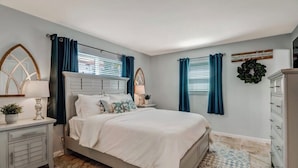 A bedroom with a bed, nightstands, a dresser, and a wall-mounted mirror.