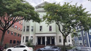 A multi-story building with a central entrance, flanked by trees and parked cars. - Spacious 4 bedroom apartment in adorable Boston with Central AC (Boston)