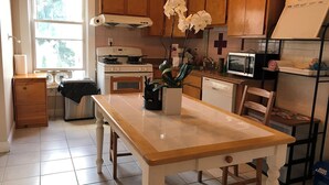 A kitchen with wooden cabinets, a stove, a microwave, and a dining table. - Spacious 4 bedroom apartment in adorable Boston with Central AC (Boston)