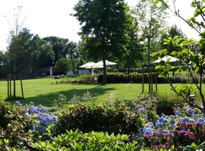 A well-maintained garden with a lawn, trees, and flower beds. - Romantic Room Nestled in Scenic Green Spaces with Direct Access to Park (Ootmarsum)