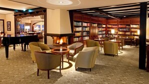A library with bookshelves, a fireplace, and seating areas.