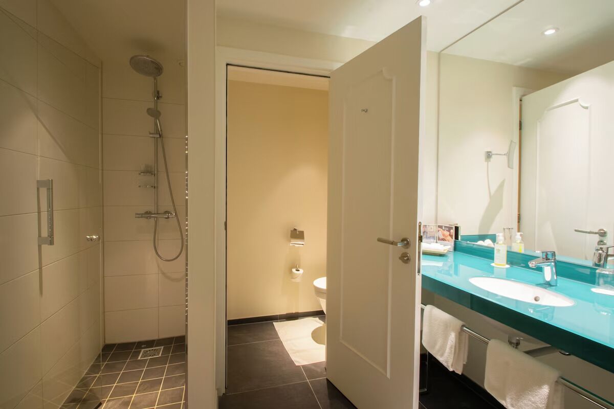 Een badkamer met een douche, toilet en wastafel met spiegel.