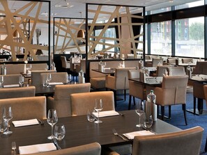 Un restaurante con varias mesas y cabinas, cada una dispuesta con copas de vino y cubiertos.