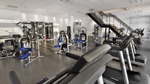 Ein Fitnessstudio mit Laufbändern, Kraftgeräten und einer Treppe.