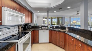 Een moderne keuken met een ingebouwde magnetron, kookplaat en vaatwasser, houten keukenkastjes en een groot raam met uitzicht op de omgeving.