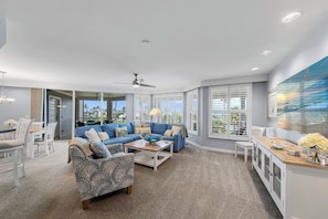A spacious living room with a blue sofa, a patterned armchair, and a wooden coffee table.