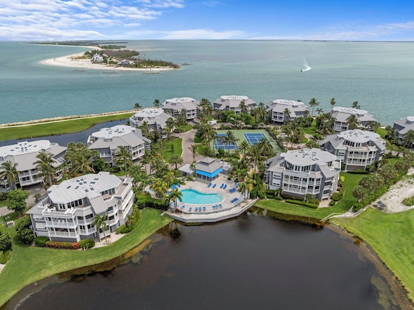 A resort with multiple buildings, a swimming pool, and a view of the ocean.